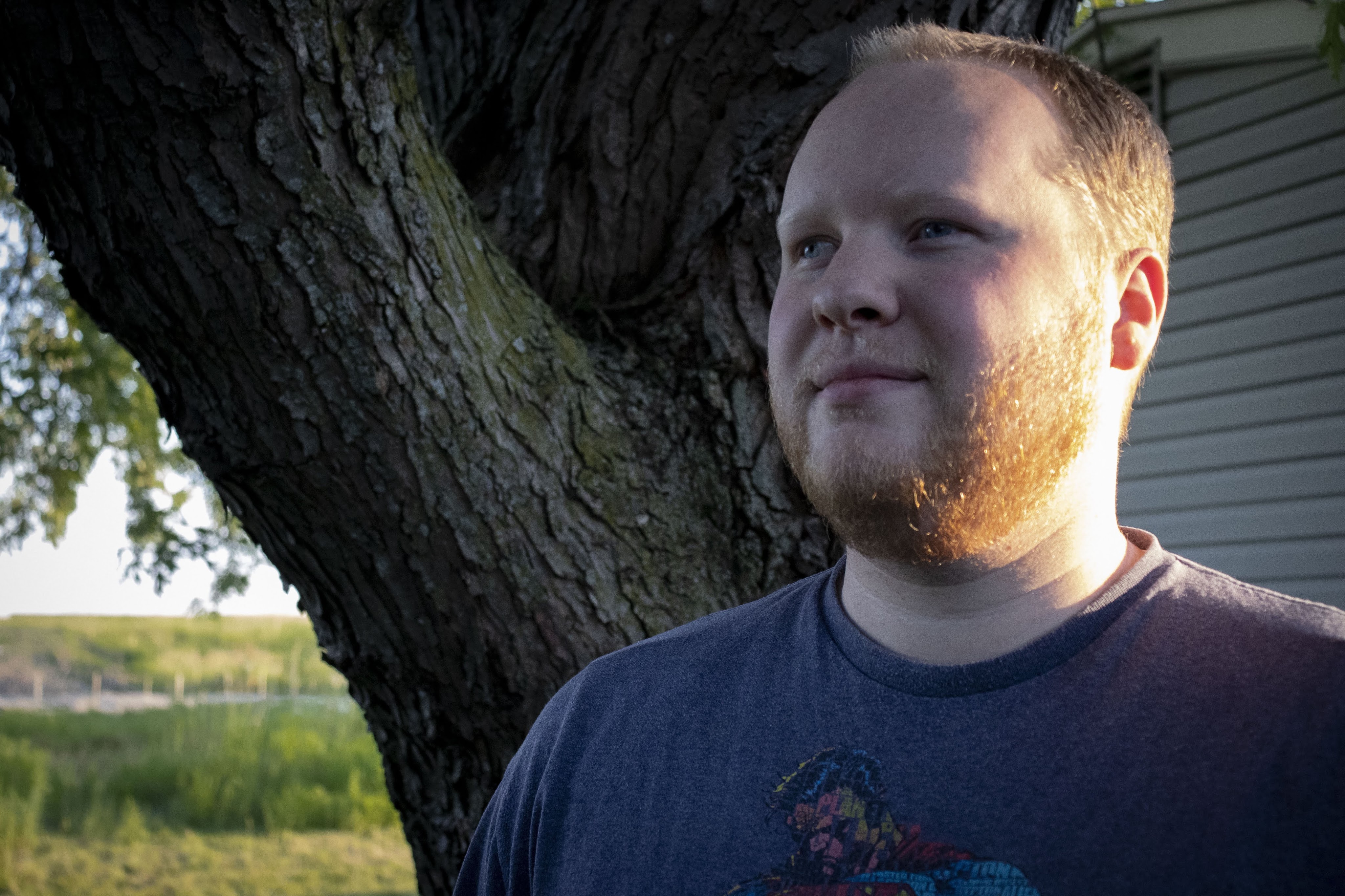 Nathan Orgill photograph tree grass blue shirt beard looking left