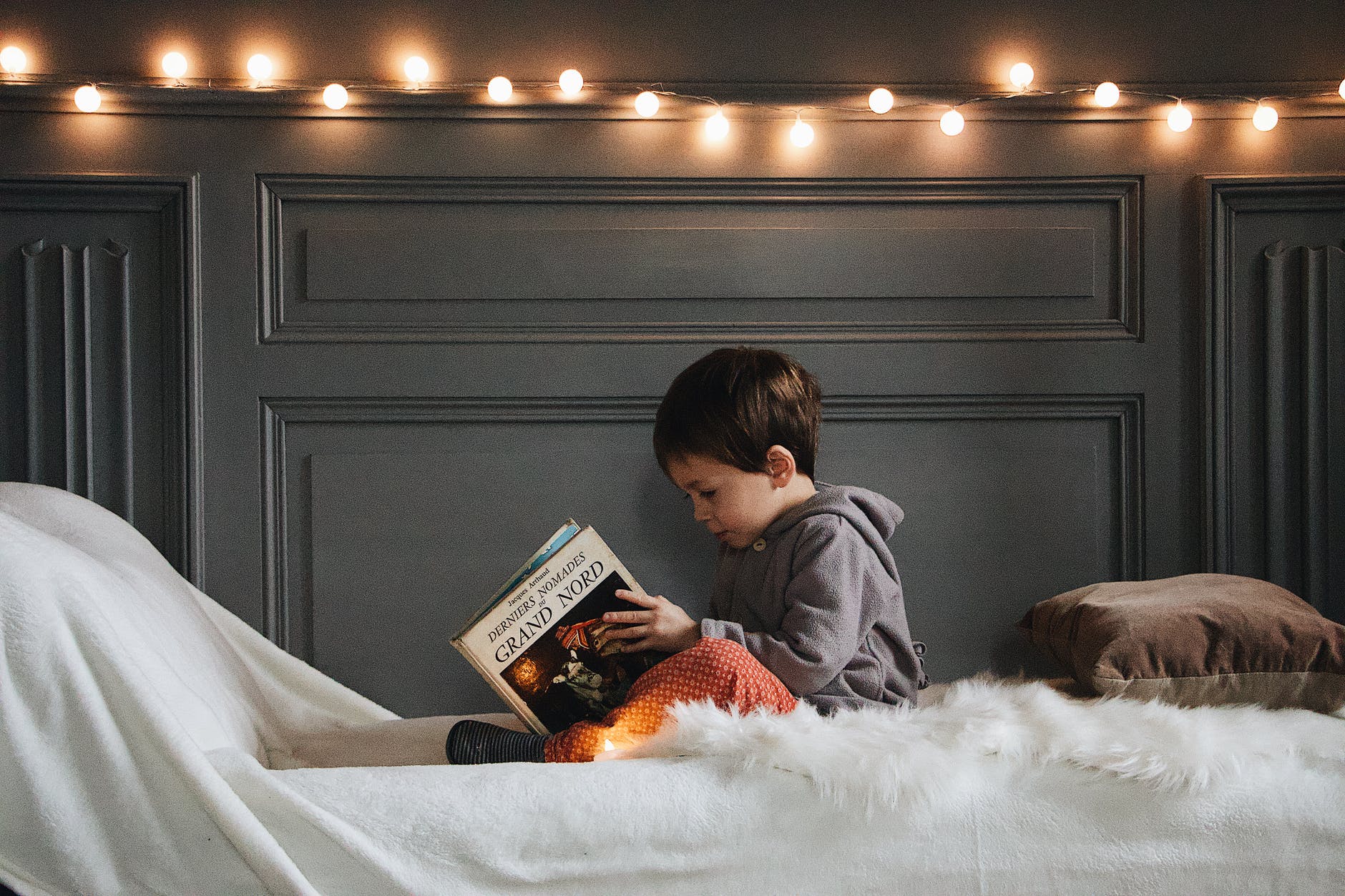 kid sitting on a cushion reading from a book