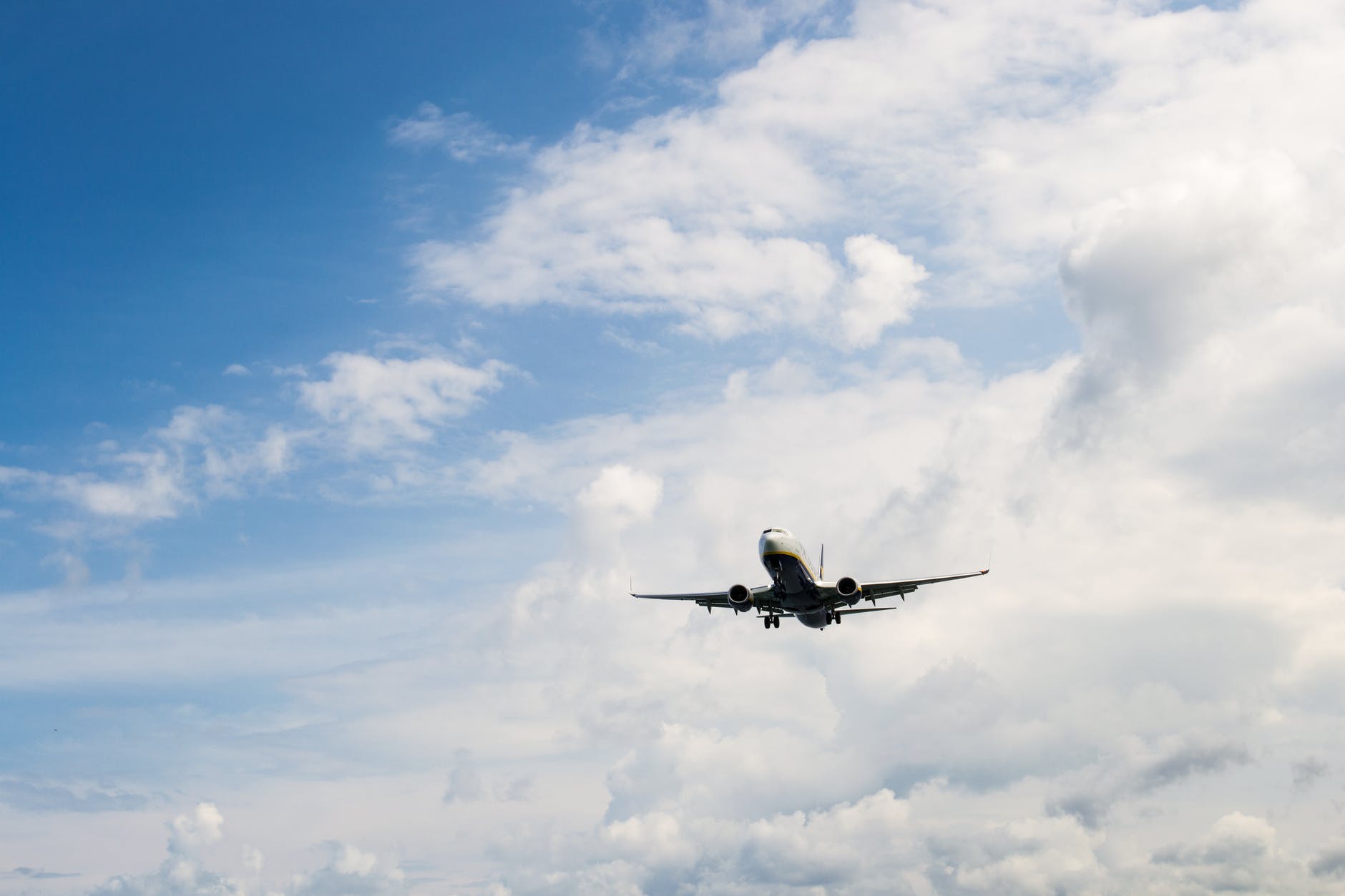 airplane flying through white clouds and blue sky