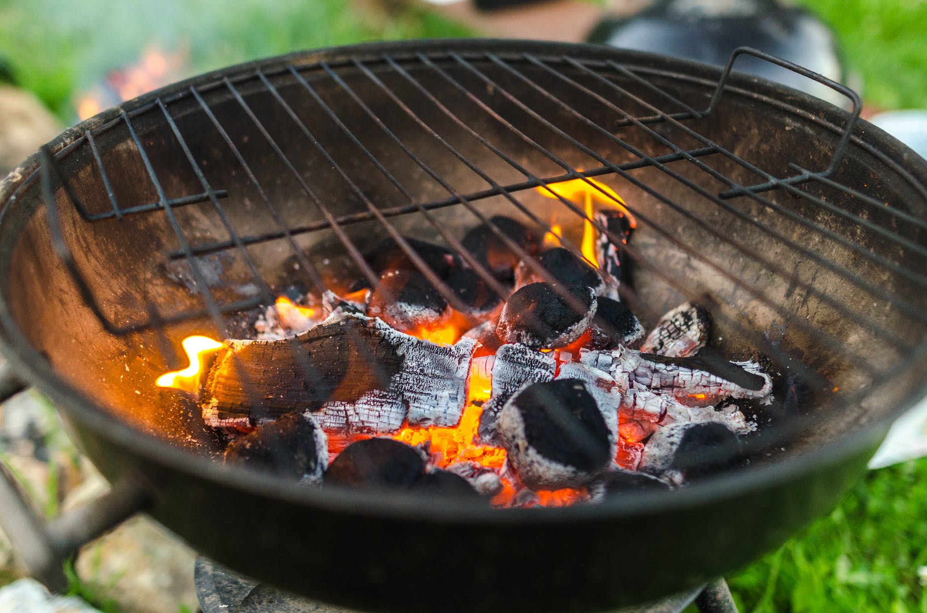 wood and charcoal burning in a metal grill in a backyard