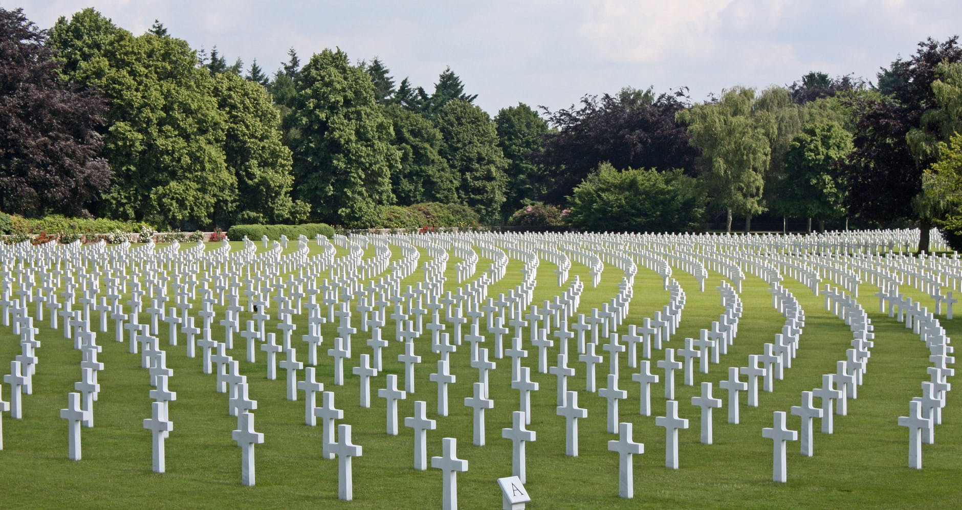 Cemetery full of white crosses on green grass