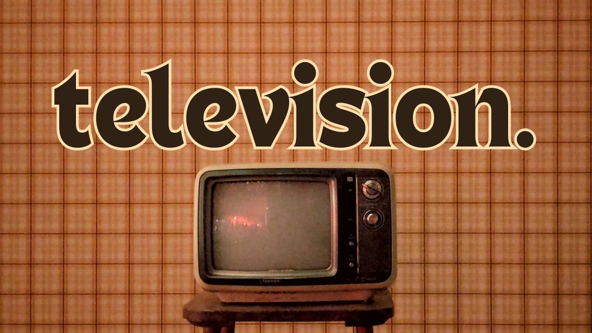 vintage photo of a television on a wood table with brown plaid wallpaper as the background